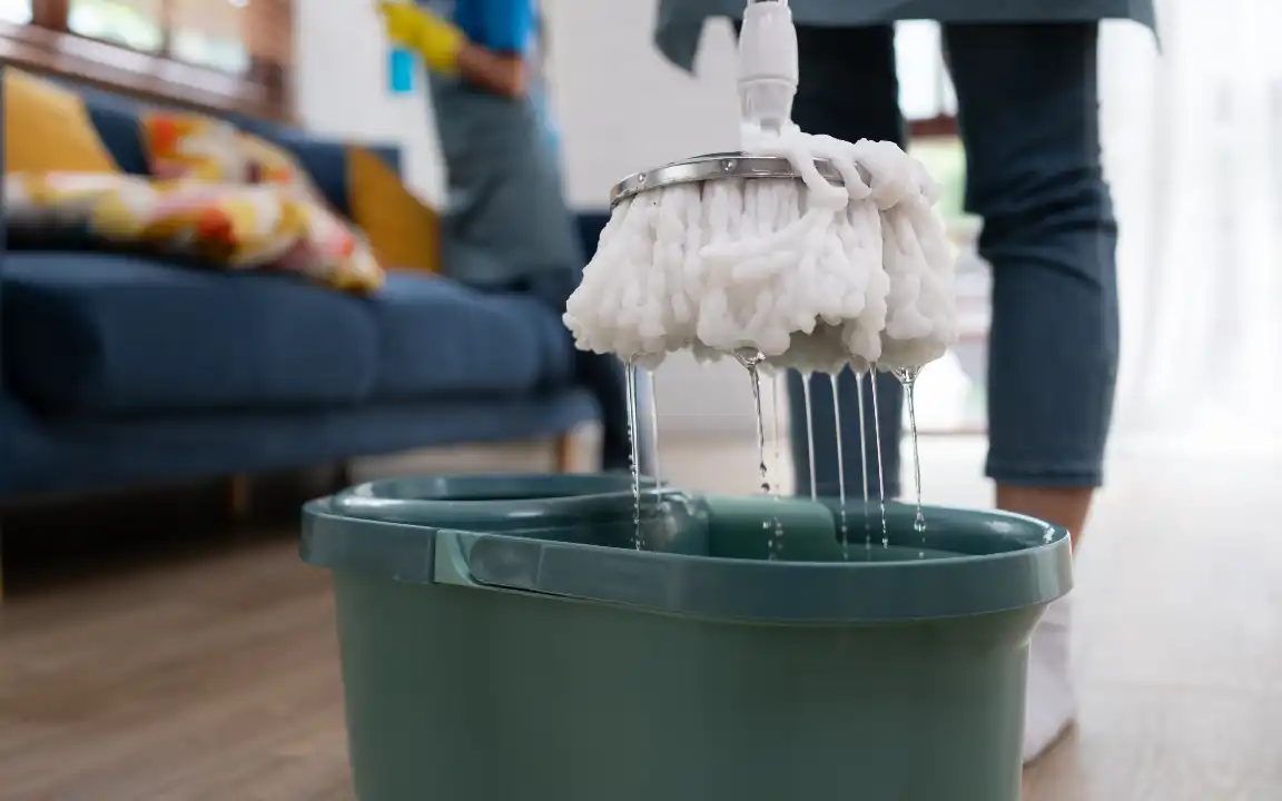Close-up of mop and bucket with assorted cleaning products